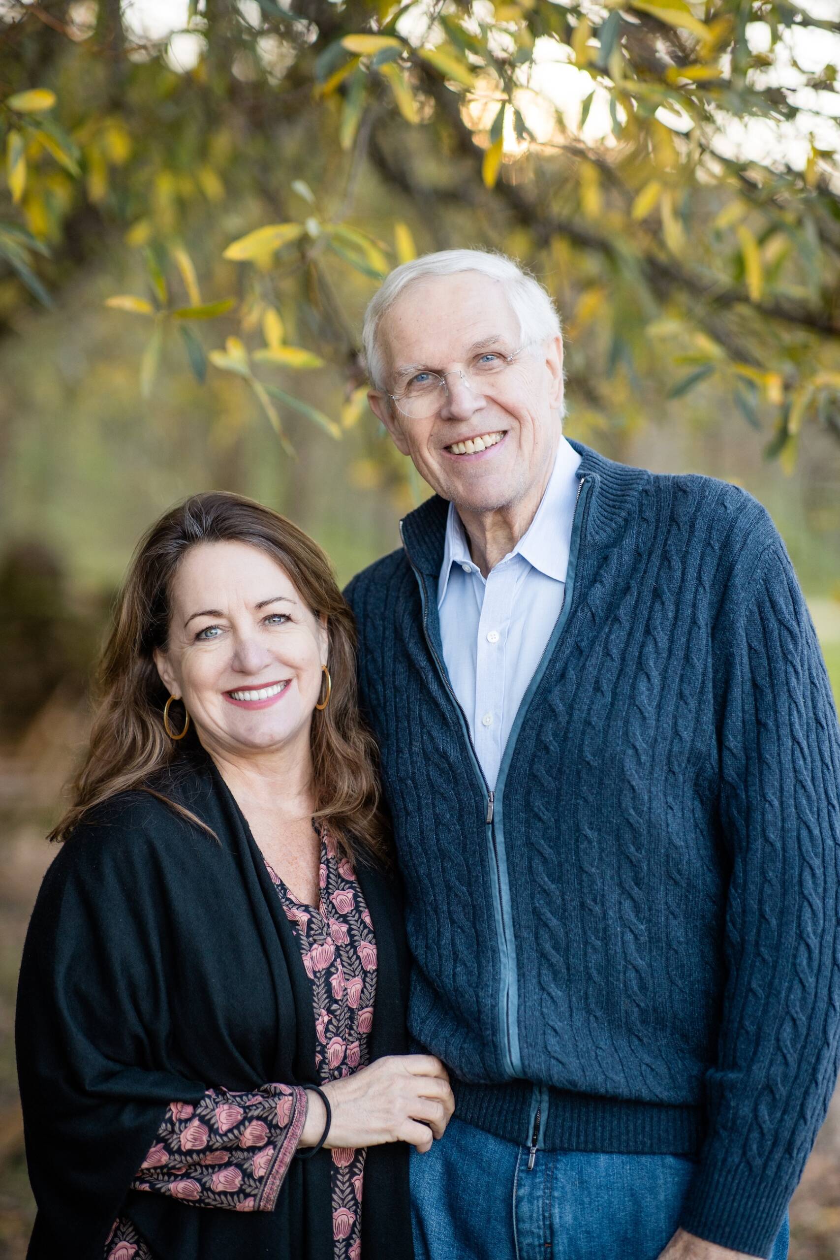 Kelley & Jim Bailey, smiling, outdoors under a tree branch