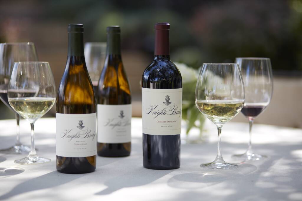 Cab Sauv & Chardonnay on sunlit outdoor table with white cloth.