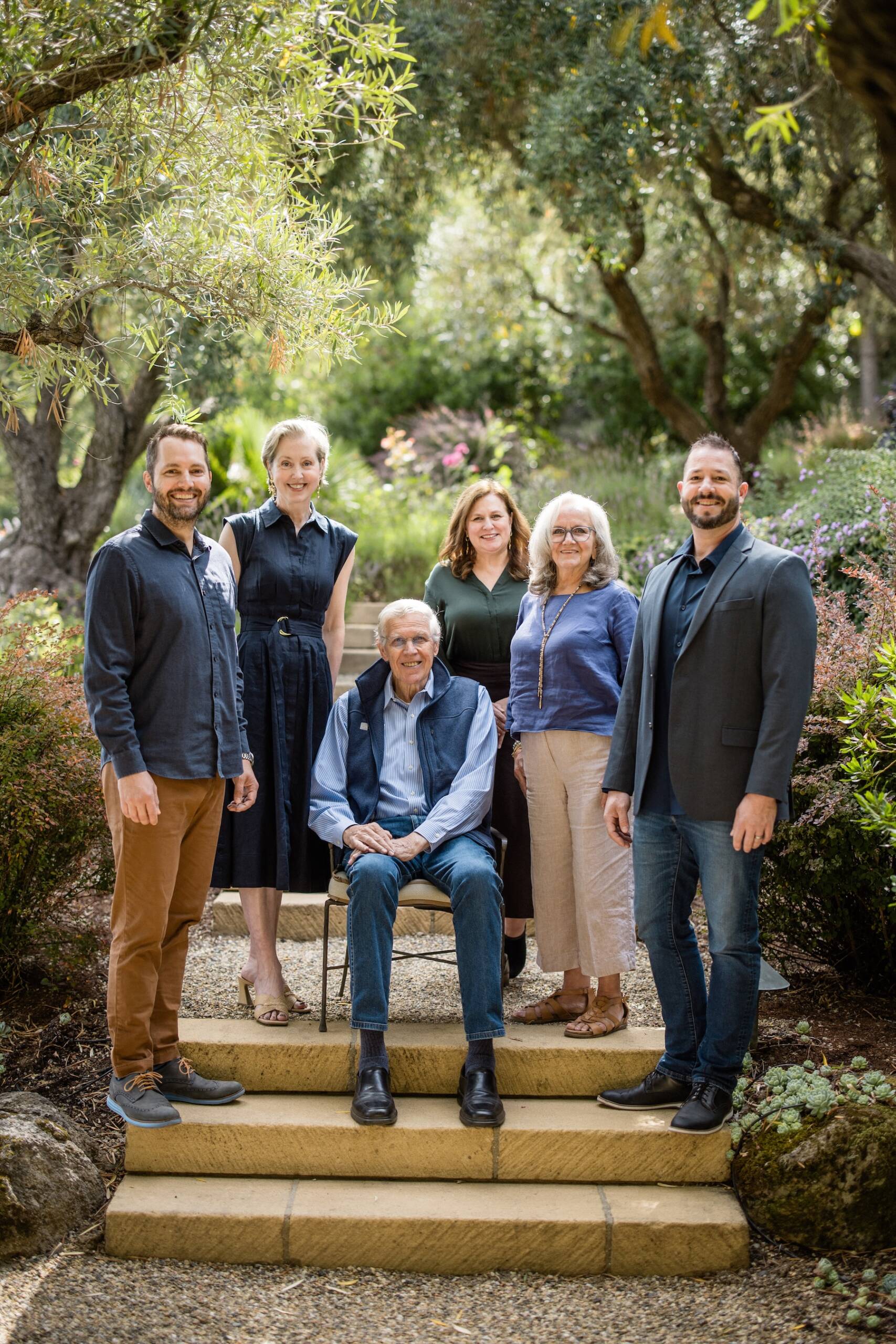 Members of the Knights Bridge staff stand on garden steps, surrounding Jim Bailey, who is sitting in a chair.